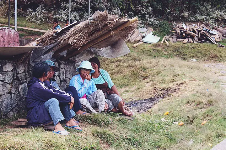 Varios campesinos se protegen del sol bajo un techo improvisado de pencas.