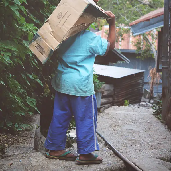 Un señor carga un paquete en el camino hacia el pueblo.