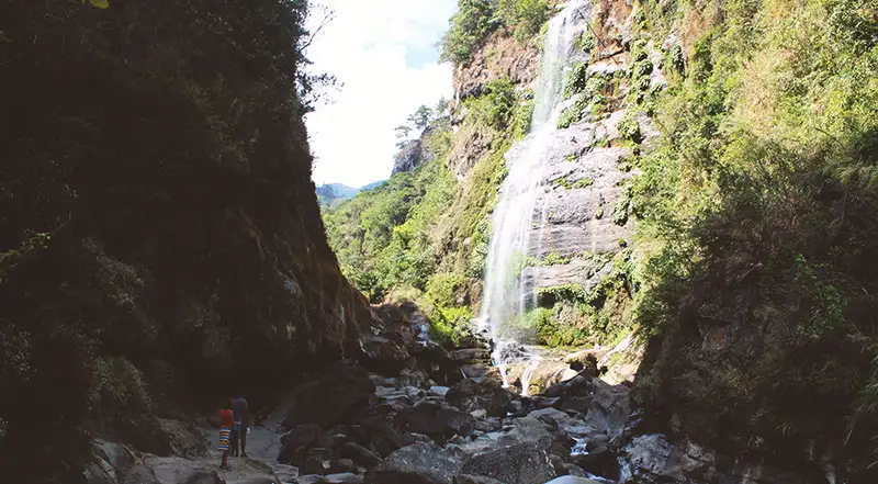 Las cataratas se ven en la distancia al atravesar un risco encubierto en sombras.