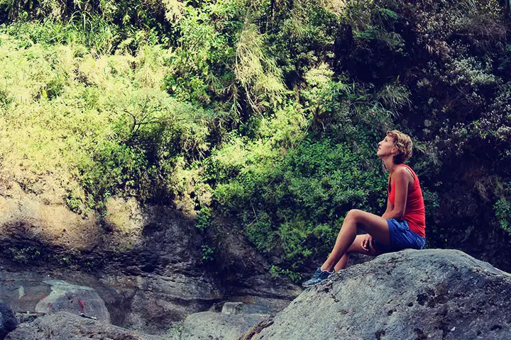 Stef contempla las cataratas sentada sobre una roca.