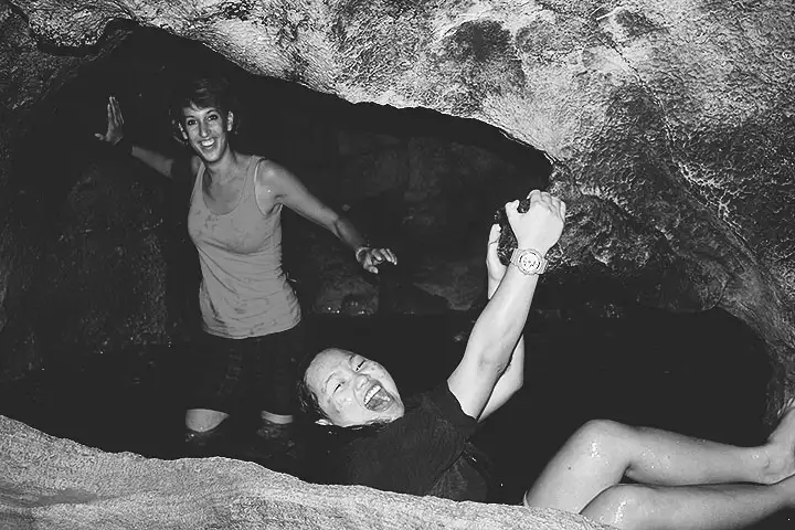 Stef posa en el agua mientras Xopau intenta hacer deep water solo. Foto en blanco y negro.